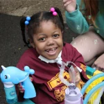 A girl smiling while playing with bubbles