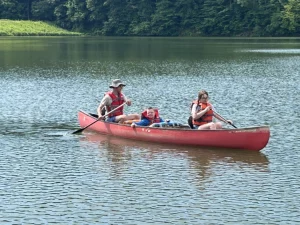 A camper and two counselors in a canoe